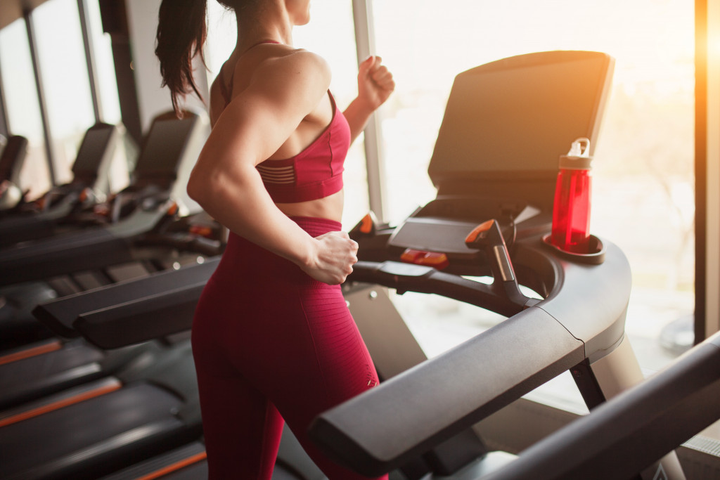 Woman wearing gym wear running on treadmill in gym 