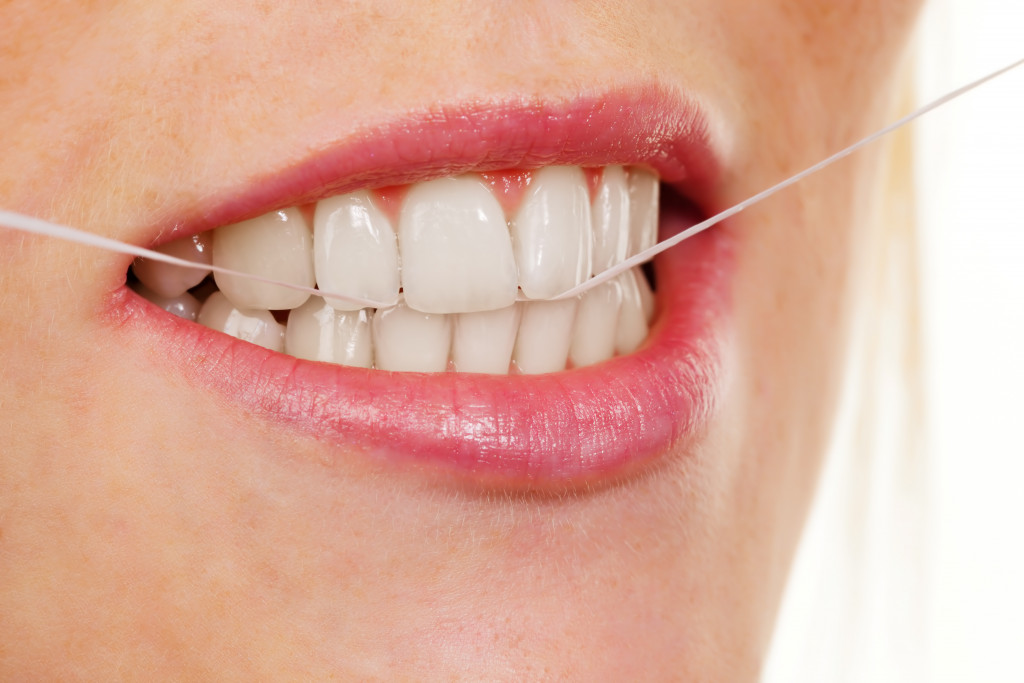 A person using a dental floss to clean their teeth