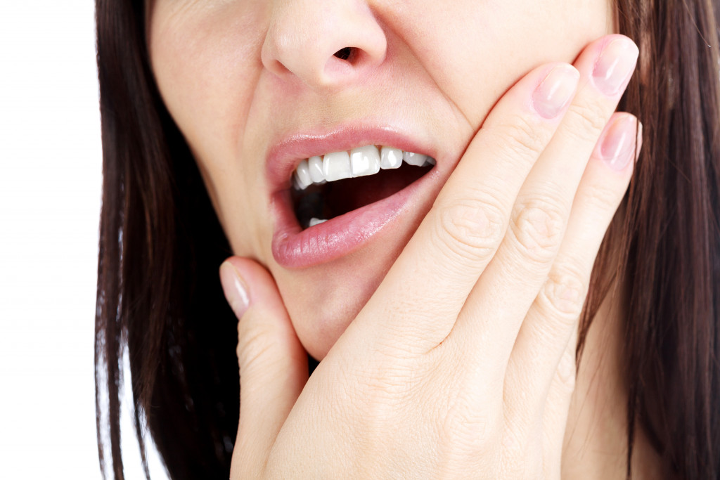 young woman holding her jaw while opening her mouth