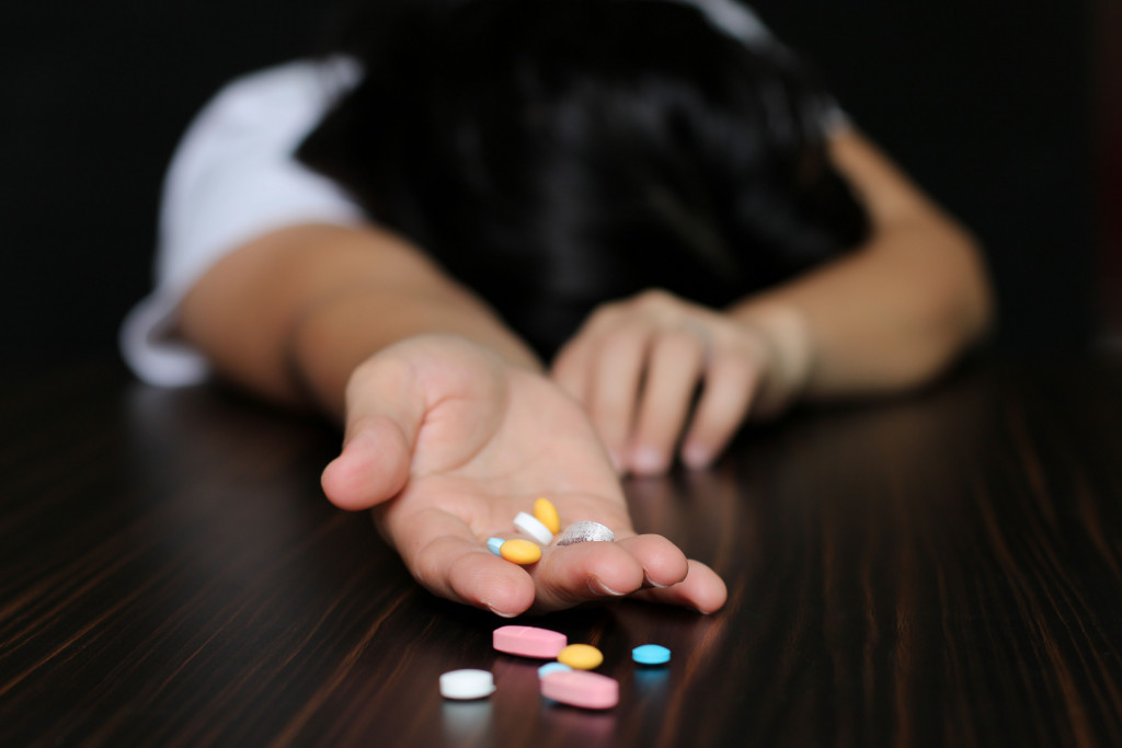a woman laying down with pills in her hand