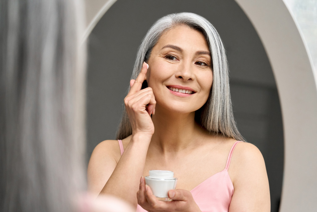 A mature woman applying moisturizer to her face