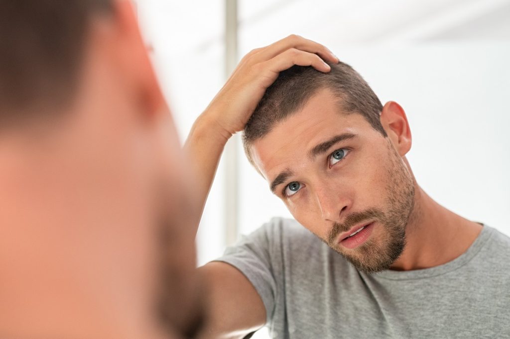 man checking his hair at the mirror