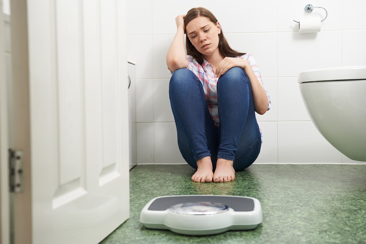 unhappy woman with weighing scale in the bathroom